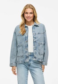 Hellblaue Jeansjacke mit Knopfverschluss, Brusttaschen und lockerer Passform. Verwaschenes Design und kontrastierende Nähte.