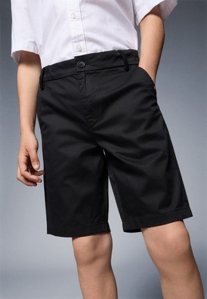 Sorte shorts lavet af letvægtsstof. Har knaplukning og sidelommer. Kantene slutter lige over knæet. Enkel, ren design.