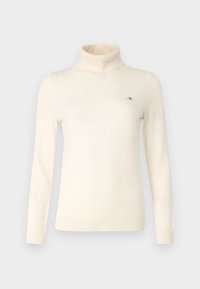 Krémový rolák vyrobený z měkké tkaniny, s dlouhými rukávy a malým vyšitým logem na hrudi. Hladká textura.