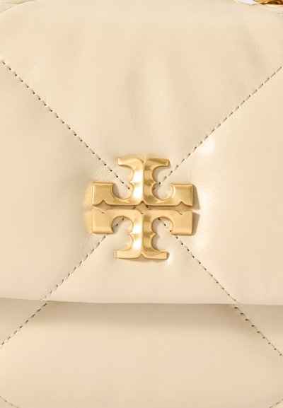 Τσάντα από δέρμα σε κρέμα απόχρωση με διαμαντένια γαζιά, χρυσό λογότυπο στη μέση και αντίθετη σκούρα ραφή.