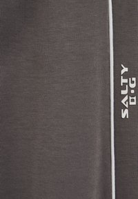 Gråt stof med en tekstureret overflade, med en hvid stribe langs den ene side og logoet "SALTY D.I.G" i hvid skrift.