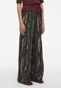 Pantalons à jambes larges en tissu noir texturé avec des rayures verticales crème, dotés d'une taille élastique et d'une silhouette ample.