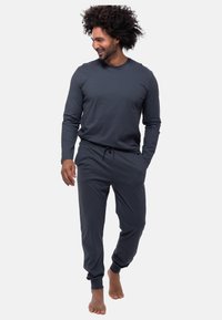 Maglia a maniche lunghe grigia scura e pantaloni jogger coordinati, realizzati in tessuto morbido, caratterizzati da una vestibilità rilassata e cinturino elastico con coulisse.