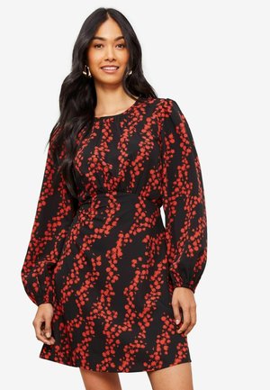 Robe noire avec des motifs floraux rouges, manches bouffantes longues, encolure froncée et taille cintrée. Tissu lisse avec une texture douce.