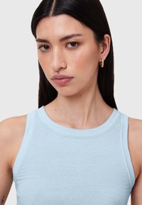 Světlomodrý žebrovaný tílko s kulatým výstřihem a širokými ramínky. Má hladkou texturu a minimalistický design.