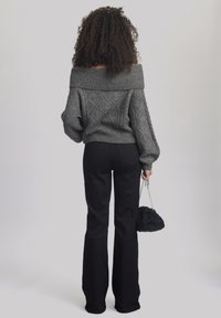 Pilka off-the-shoulder megztinis su tekstūruota deimanto raštu, derinamas su juodomis plačiomis kelnių. Laikoma tekstūruota juoda rankinė.