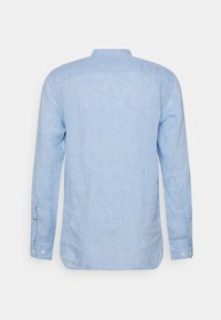 Chemise à manches longues bleu clair en lin, avec col montant, poignets boutonnés et un tissu légèrement texturé. Vue arrière présentée.