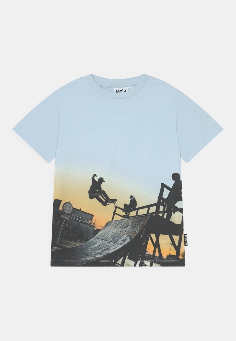 T-shirt en coton bleu clair présentant un graphisme de skateboard. Le design passe du bleu au jaune, représentant des skateurs sur une rampe.