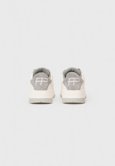 Ein Paar weiße Sneakers mit grauen Wildleder-Fersenpatches und weißen gestickten Logos, von hinten auf einem schlichten weißen Hintergrund gezeigt.
