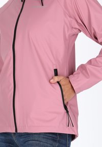 Light pink waterproof jacket featuring a front zipper, black accents, side pockets, and a smooth, shiny texture.