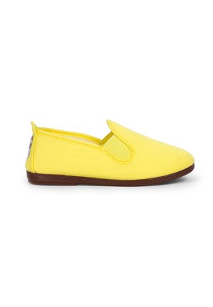Chaussure à enfiler en toile jaune avec un bout rond, des accents élastiques sur les côtés et une semelle en caoutchouc marron. Détails de couture le long des bords.
