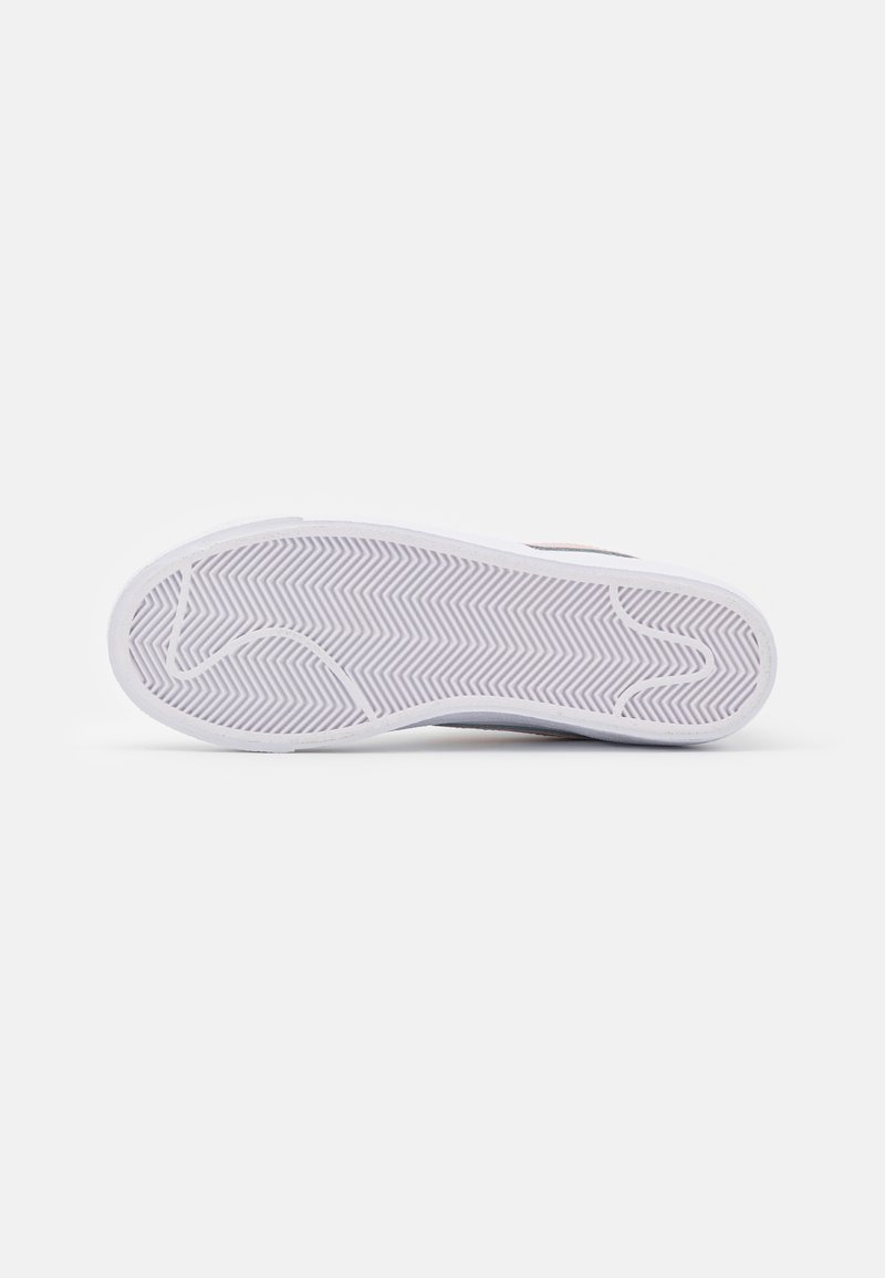 Suela de zapatilla blanca con un patrón de espiga texturizado, borde curvado y material de goma suave.
