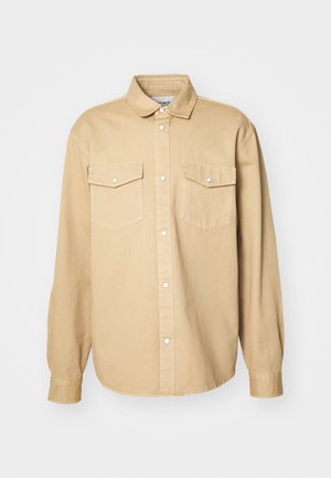 Beige skjorte med knapper laget av bomull, med klassisk krage, to brystlommer og lange ermer med knapper ved håndleddene.