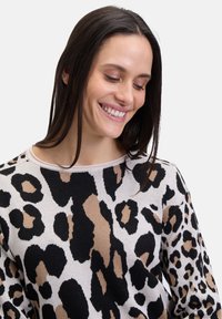 Strickpullover mit einem Leopardenmuster in Schwarz, Beige und Creme; runder Halsausschnitt und weicher Textur.