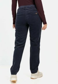 Donkerblauwe corduroy broek met een elastische tailleband, taps toelopende broekspijp, zijzakken en een achterzakdetail.