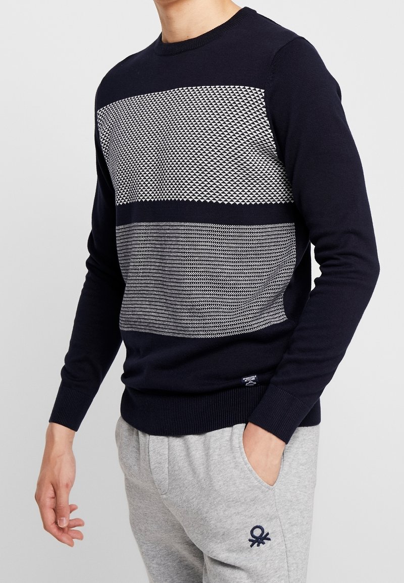 Marinblå tröja med strukturerade grå horisontella ränder och geometriska mönster. Ribbad mudd och fåll, figurnära design, tillverkad av stickad tyg.