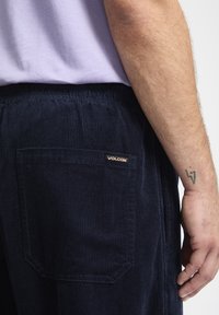 Pantalons en velours côtelé bleu marine avec une surface texturée, une taille élastique et une poche arrière arborant un petit logo Volcom doré.