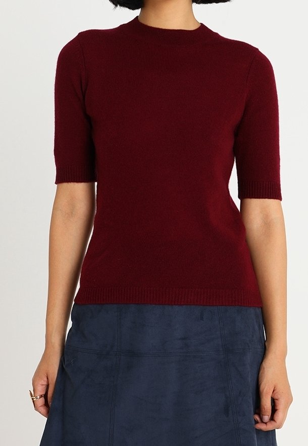 Burgundy lyhythihainen neulepusero, jossa on pyöreä kaula-aukko ja ribbausut sekä sininen teksturoitu hame.