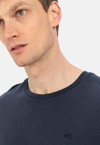 Mørkeblå bomulds T-shirt med rund hals, der har et lille broderet logo på brystet. Glat tekstur og regular fit.