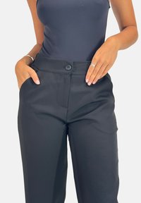 Zwarte op maat gemaakte broeken met een gladde textuur, voorzien van een knoopsluiting, zijzakken en een aangesloten taille voor een gestroomlijnde uitstraling.