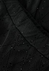 Czarna tkanina teksturowana z plecionym wzorem w diamenty i małymi otworami, ozdobiona rozsypanymi cekinami dla dodatkowego detalu.