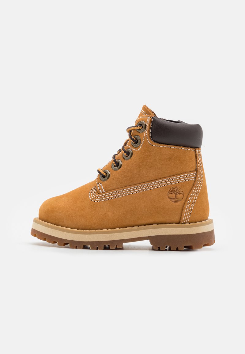 Beige Wildleder Stiefelknöchel mit einem braunen Lederkragen, runder Zehenform und kontrastierenden weißen Nähten. Verfügt über Metallösen und eine strukturierte Gummisohle.