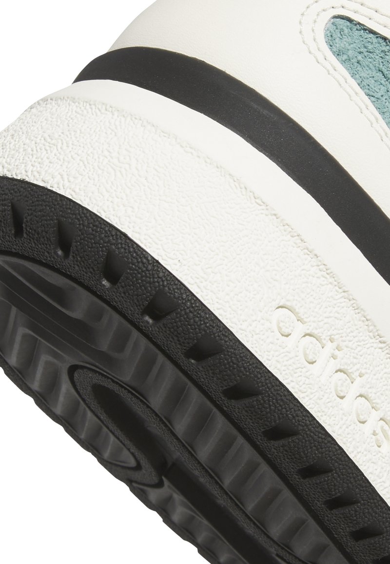 Baskets blanches avec un dessus texturé, des accents turquoise et une semelle en caoutchouc noir. Marquage notable sur le côté et lignes contrastantes en matériaux.
