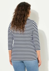 Blau-weißer gestreifter Langarmshirt, aus weichem Baumwollmaterial, eng anliegendes Design, abgerundetem Saum, kombiniert mit hellblauen Jeans.