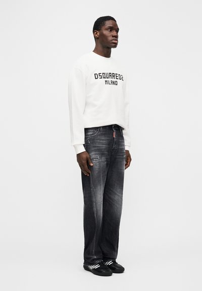 White sweatshirt with "DSQUARED2 MILANO" in black letters, paired with distressed dark gray wide-leg jeans and black shoes with white stripes.