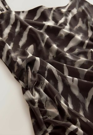 Schwarz-weißer Stoff mit einem strukturierten Gewebe, der sanfte Drapierungen und einen subtilen Glanz aufweist, was ein fließendes Erscheinungsbild erzeugt.