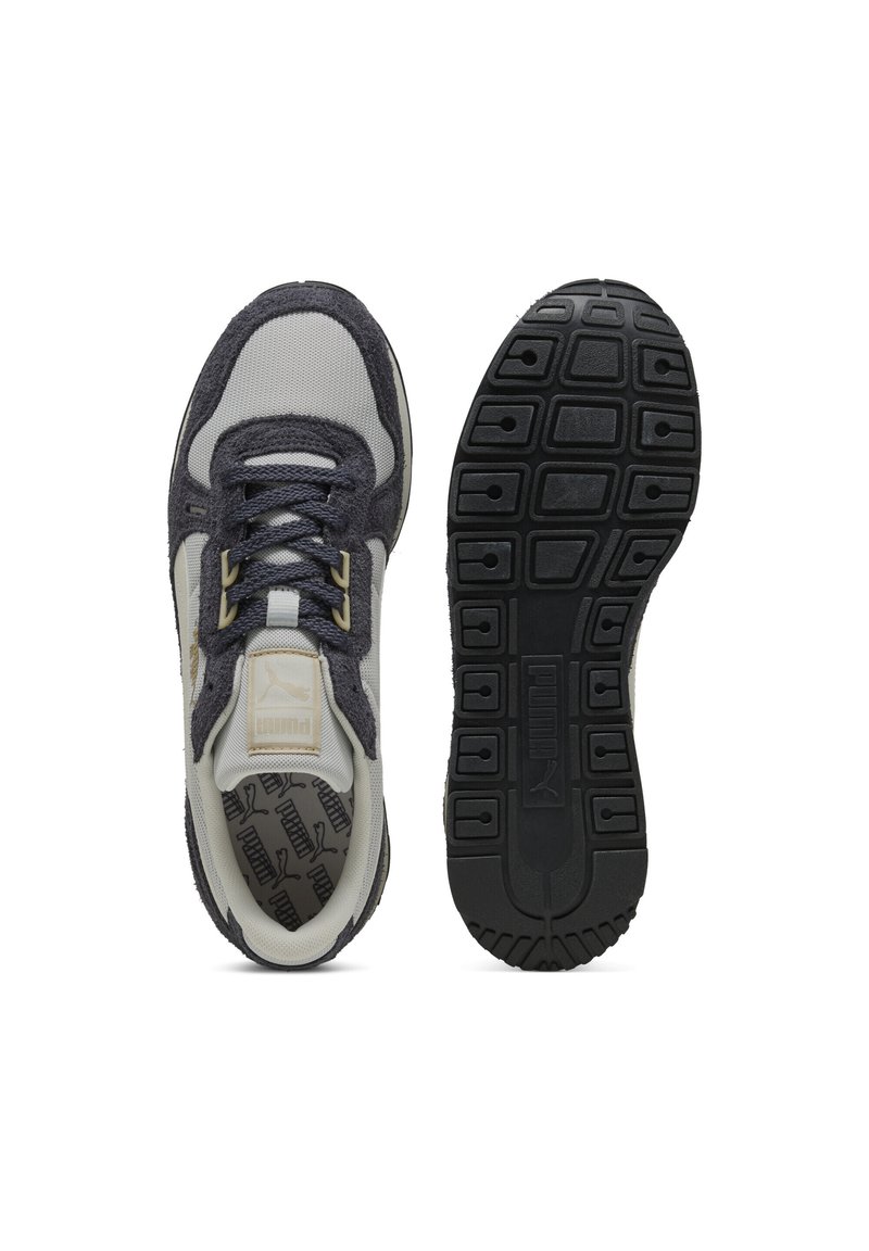 Botte gauche montrant un dessus en maille gris et marine avec des lacets, semelle de la chaussure droite en caoutchouc noir avec un motif en blocs et logo Puma centré.