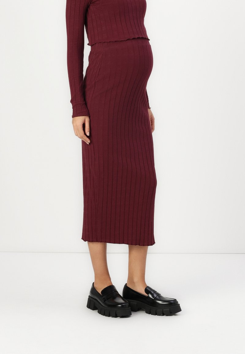 Burgundská pletená těhotenská blůza s rib strukturou a midi sukně s přiléhavým střihem. Černé masivní mokasíny dotvářejí outfit.