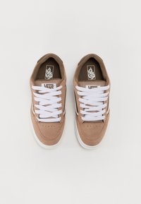 Zapatillas de ante marrón con cordones blancos, collar acolchado, paneles de malla y suelas de goma. Presentan un logotipo distintivo en la lengua y el costado.