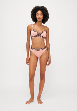 Pink bralette and matching bikini set featuring black Moschino branding. The bralette has thin straps and a cross design, with a smooth texture.