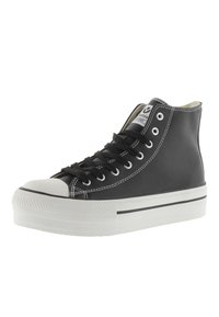 Zapatillas de lona negras de caña alta con punta de goma blanca, suela blanca y costuras en contraste. Cuenta con un diseño de cordones y etiqueta del logo en la lengüeta.