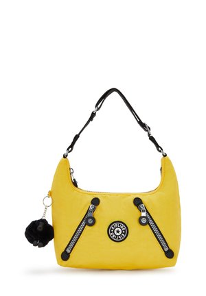 Yellow handbag with a soft texture, black zippers, and accents; features a round logo and a detachable black pom-pom keychain.