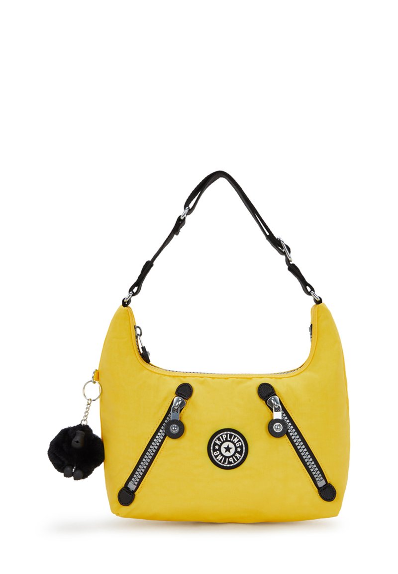 Bolso amarillo con una textura suave, cremalleras y detalles en negro; presenta un logo redondo y un llavero de pom-pom negro desmontable.