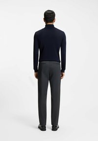 Navy long-sleeve knit top paired with gray tailored trousers. The outfit features a slim fit and subtle texture, complemented by black shoes.
