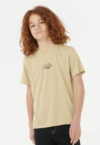 Camiseta de algodón beige con mangas cortas y un cuello redondo. Presenta un pequeño diseño gráfico multicolor en el pecho.