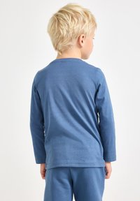 Blaues Langarmshirt aus Baumwolle mit rundem Ausschnitt und entspannter Passform, kombiniert mit passenden blauen Hosen. Geschmeidige Textur.
