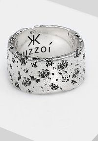 Rugged silver ring with a textured surface, featuring dark speckles and an irregular edge. Marked "925" and "Kuzzoí" on the interior.