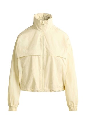 Light beige zip-up windbreaker jacket with high collar, elastic cuffs, and a yoke detail across the chest and back.