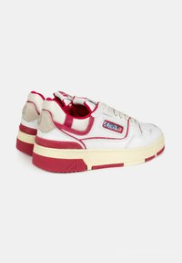 Sneaker bianche con dettagli rossi, suola in gomma testurizzata e tomaia in pelle. Presentano un collare imbottito e una patch con il logo sul lato.