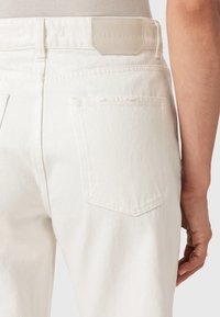 Jeans in denim bianco con vita alta, caratterizzati da un'etichetta in pelle sul retro e un taglio dritto. Include due tasche posteriori.