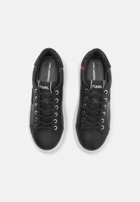 Sneaker in pelle nera con suola in gomma bianca, dotati di occhielli in argento, lacci neri e un sottile accento rosso di lato.
