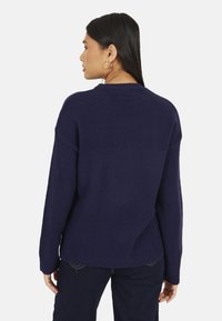 Maglione oversize blu navy con scollo a costine e maniche lunghe, realizzato in tessuto a maglia strutturato. Spalle leggermente abbassate.