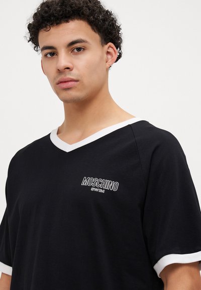 Camiseta preta com decote em V branco e mangas curtas. Apresenta um logotipo branco que diz "MOSCHINO SWIM" no peito. Tecido de textura suave.
