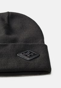 Beanie tricotat negru cu un tiv pliat, având o etichetă din piele neagră în formă de diamant, gravată cu "REPLAY 1981." Textură moale, design clasic.