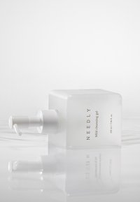 Halvgenomskinlig glasflaska med pump, fyrkantig form, frostad yta, vit pump, etikett med texten "NEEDLY Mild cleansing gel", volym 235 ml.