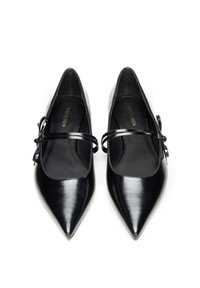 Zapatos planos de charol negro con punta puntiaguda, tiras delgadas que se cruzan en la parte superior y pequeños detalles de lazo en los costados.